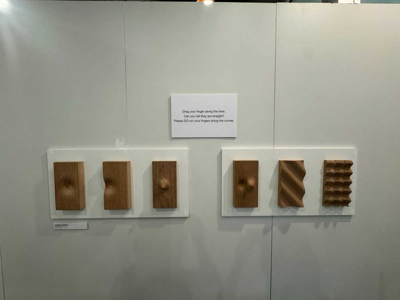Six of the boards. Visitors were invited to run a finger along the grooves and feel that the curves are straight.